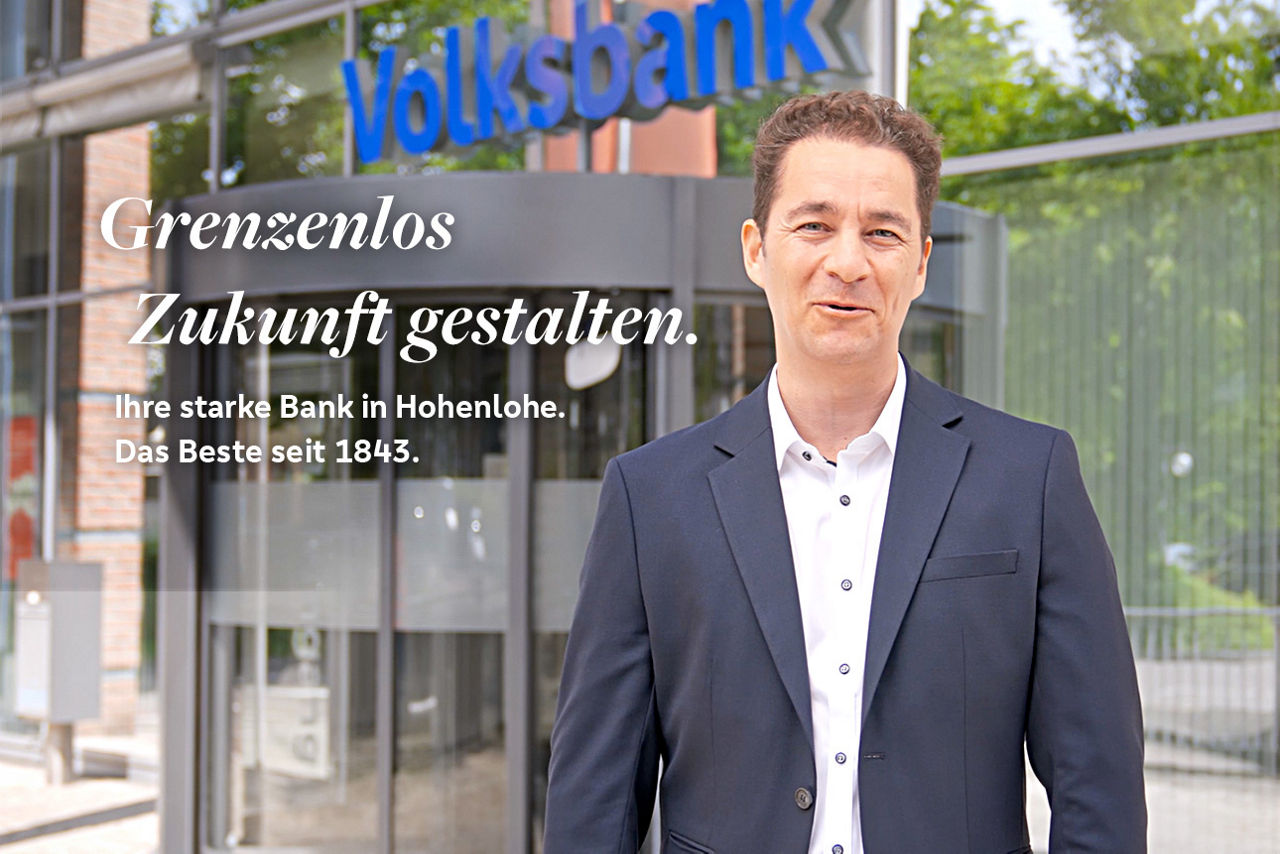 Bänker der vor Haupteingang der Volksbank Hohenlohe eG in Künzelsau steht mit der Überschrift Grenzenlos Zukunft gestalten