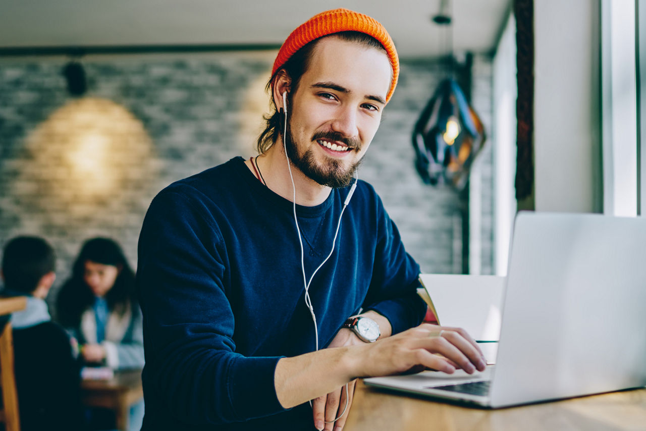 Junger Mann mit Kopfhörer vor Laptop