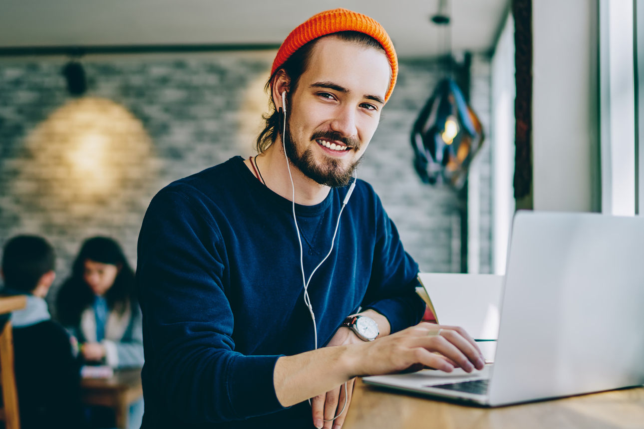 Junger Mann mit Kopfhörer vor Laptop
