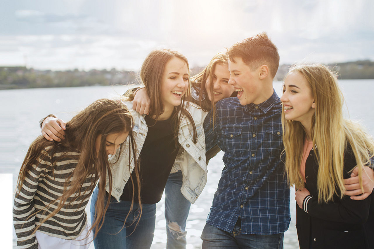 Fünf Jugendliche lachen zusammen am See