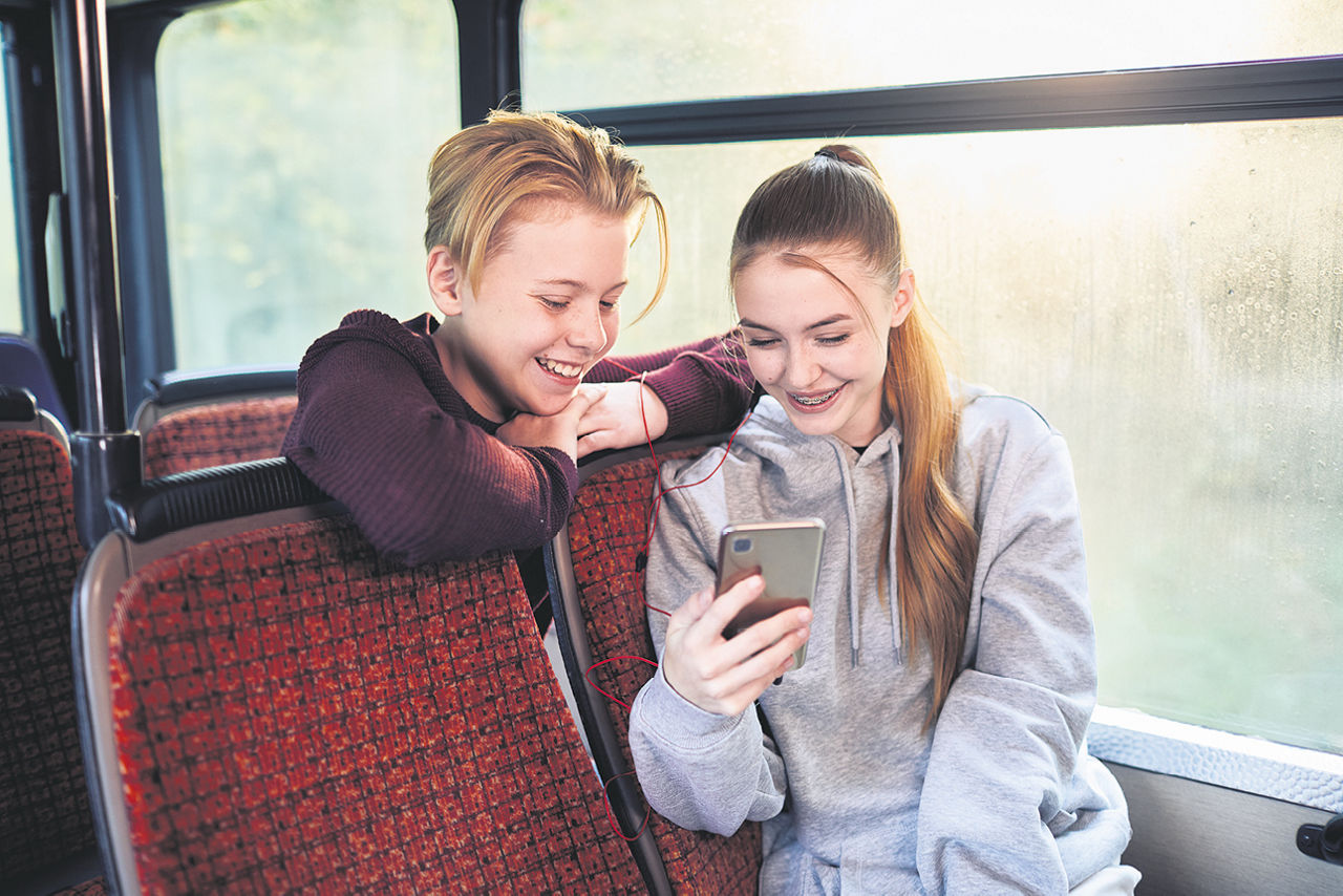 Zwei Jugendliche mit Handy im Bus