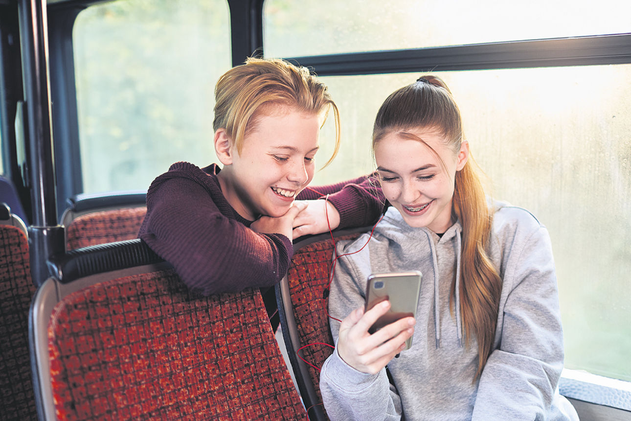 Zwei Jugendliche mit Handy im Bus