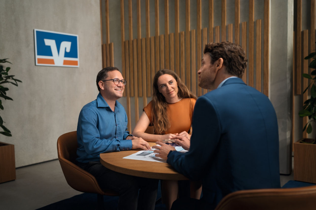 Paar im Beratungsgespräch beim Kundenberater am Tisch sitzend
