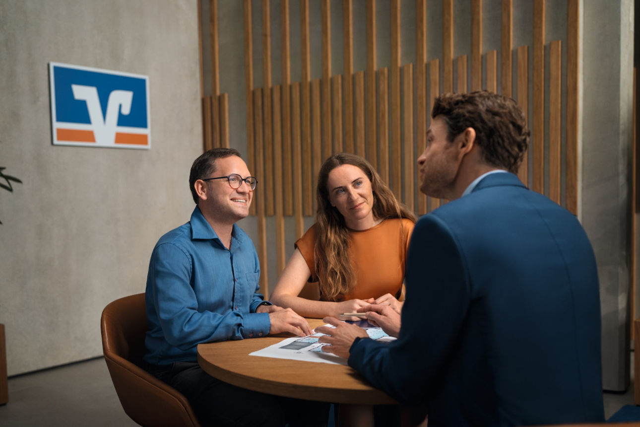 Paar im Beratungsgespräch beim Kundenberater am Tisch sitzend