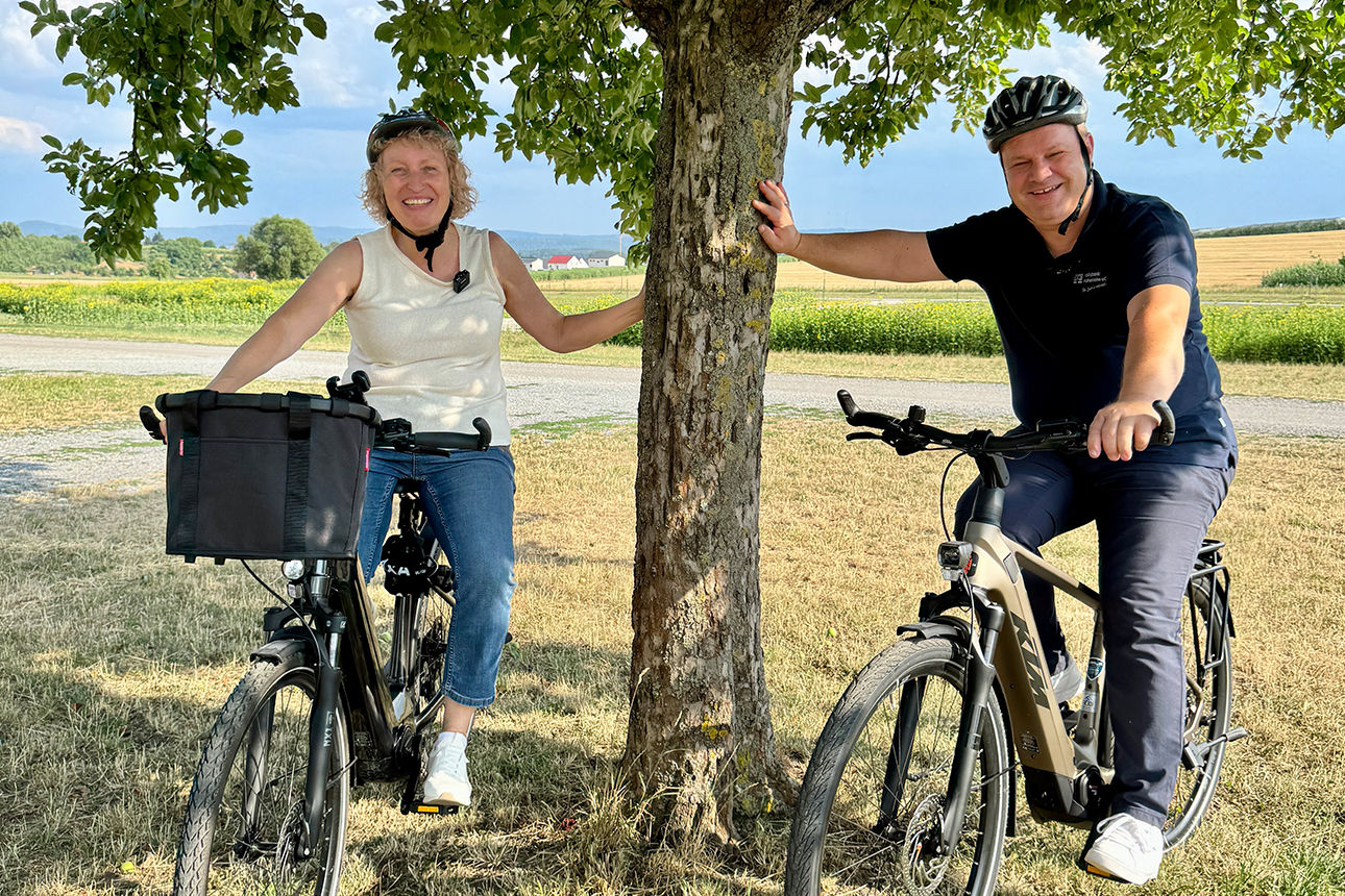 Fotos unserer Teamplayer, die sich mit dem Fahrrad an ein Baum lehnen