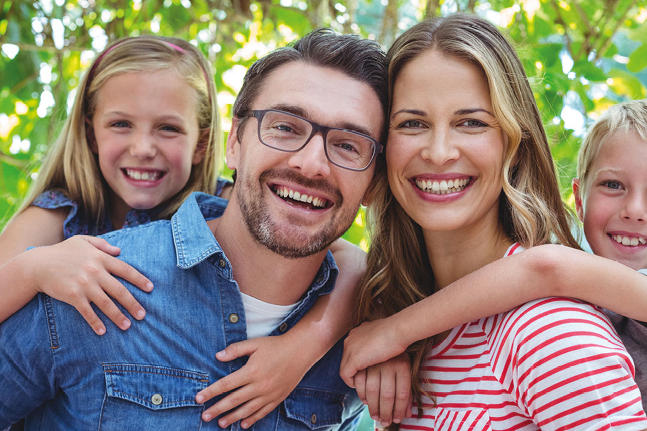 Eine Familie mit zwei Kindern lächelt in die Kamera