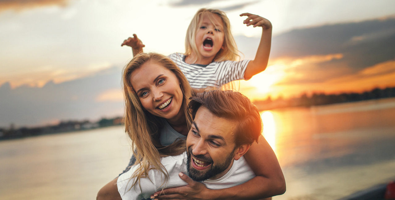 Ein junge Famile steht vor dem Sonnenuntergang an einem See