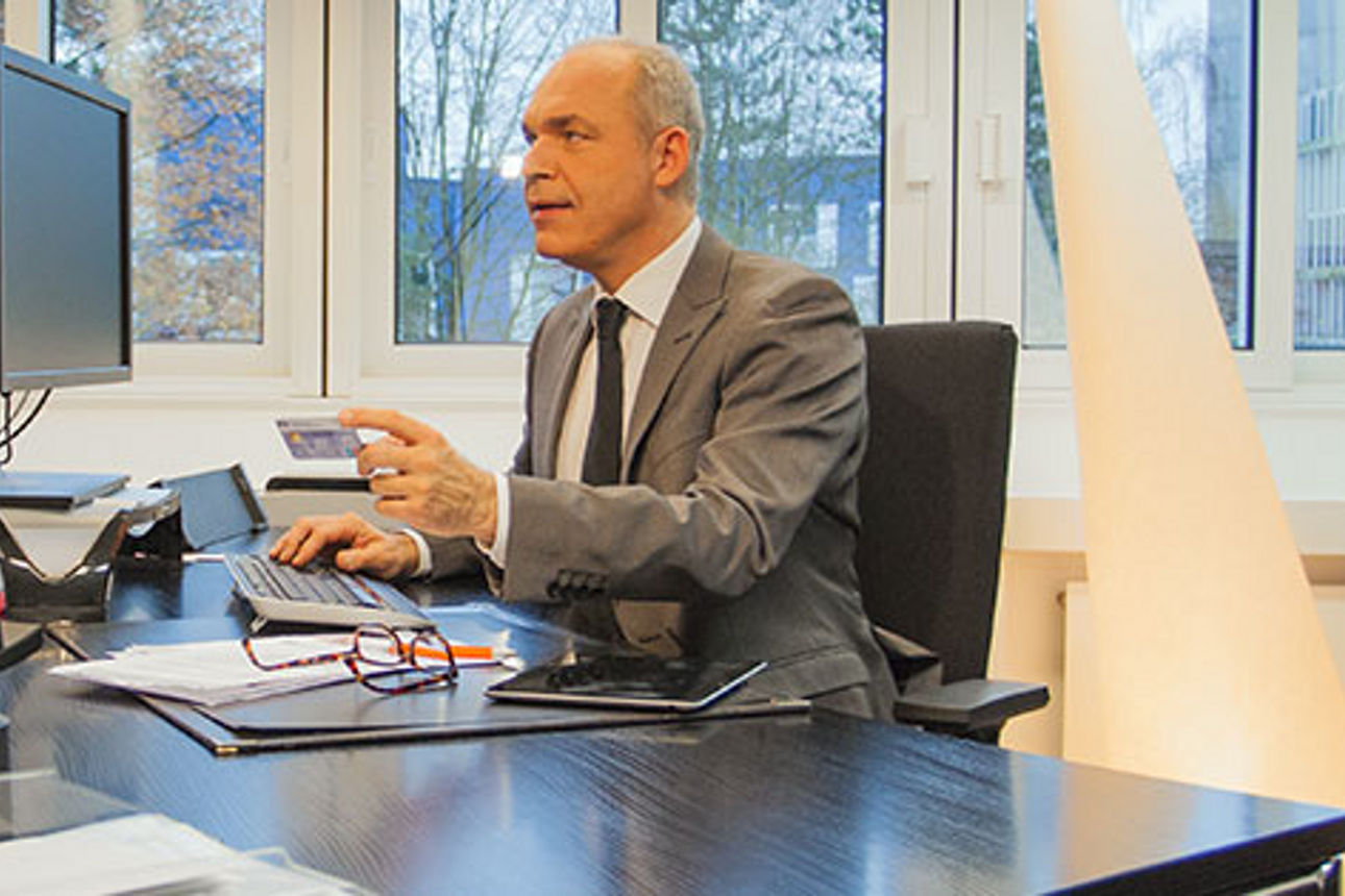 Ein Mann in einem Anzug sitzt an einem Schreibtisch und überprüft Dokumente und eine Kreditkarte.