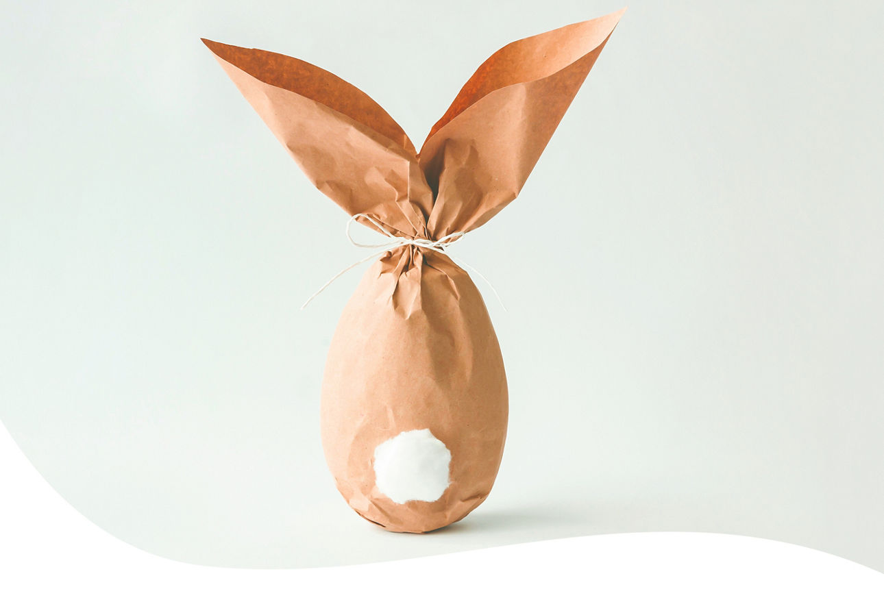 Osterei aus braunem Papier mit zwei spitzen Ohren und weißem Wattebausch als Schwanz