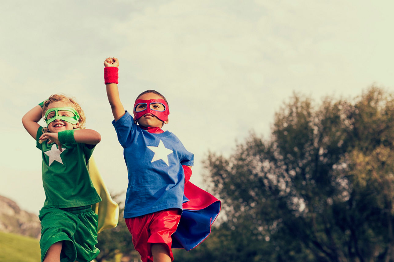 Zwei kleine Jungs mit Superhelden Umhang laufen ins Bild.