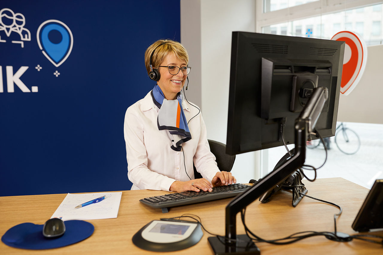 Mitarbeiterin mit Headset vorm Bilschirm