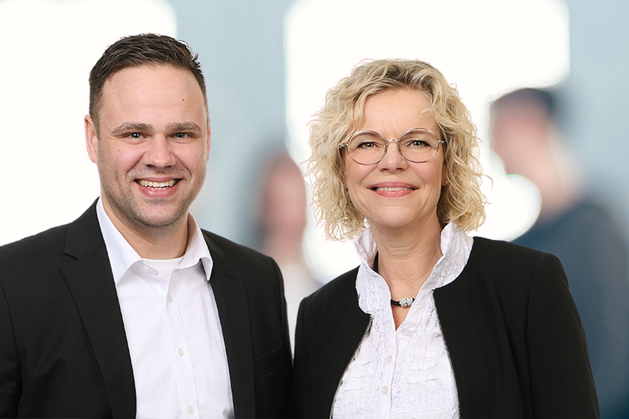 Ein Mitarbeiter und eine Mitarbeiterin der Brandenburger Bank in schwarz weißer Kleidung