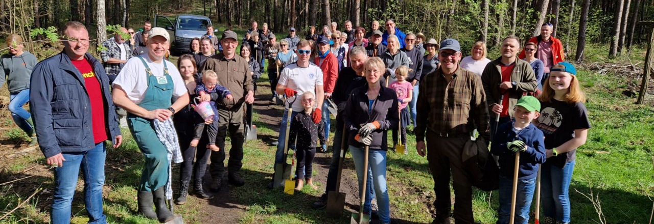 Eine Gruppe von circa 50 Menschen mit Spaten im Wald