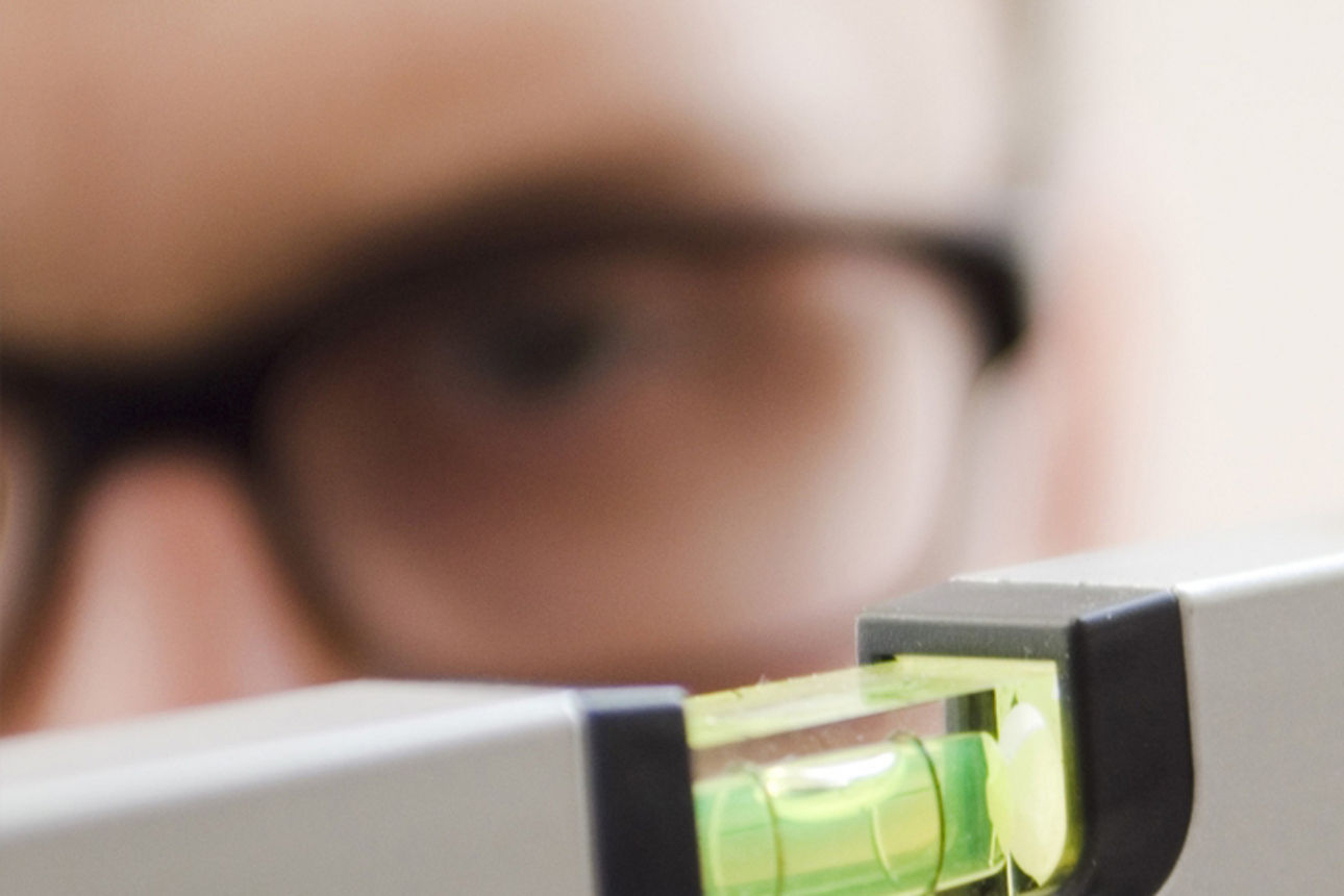 Ein Mann überprüft die Ausrichtung eines Tisches mit einer Wasserwaage