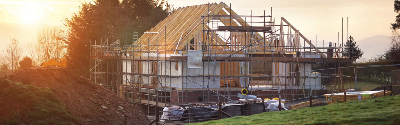 Ein im Bau befindliches Haus, umgeben von Baugerüsten, die auf laufende Bauarbeiten und Renovierungen hinweisen.
