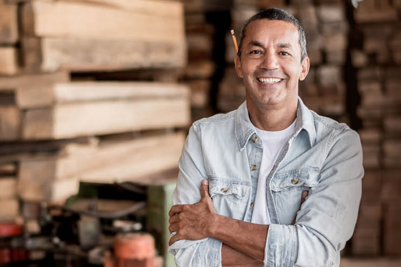 Ein Mann steht vor einem großen Holzstapel