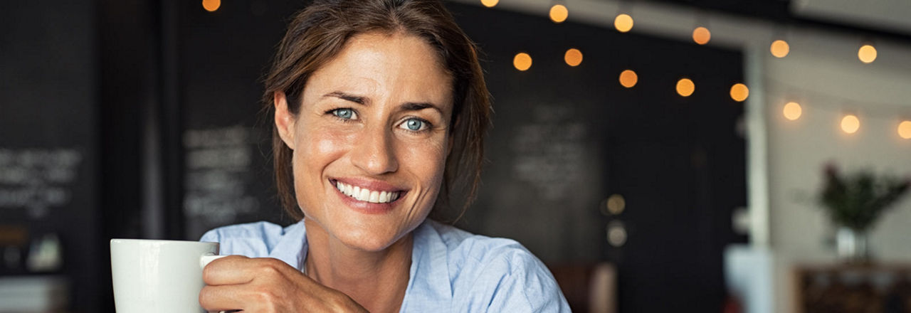 Lächelnde Frau hält Kaffetasse in der Hand