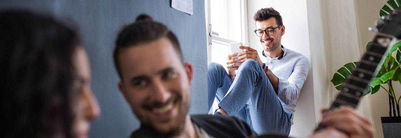 Grupp junger Menschen, einer schaut auf sein Handy