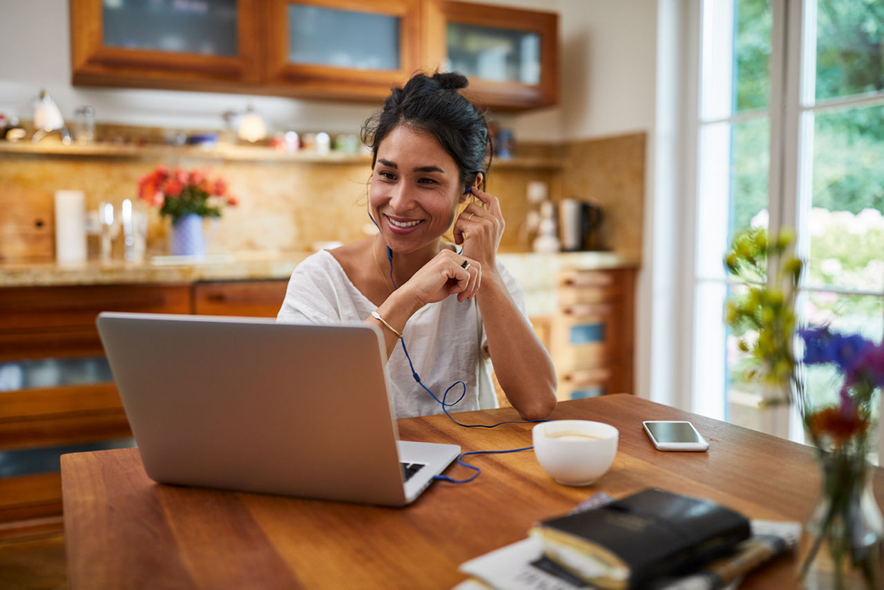 Frau sitzt im Wohnzimmer am Laptop