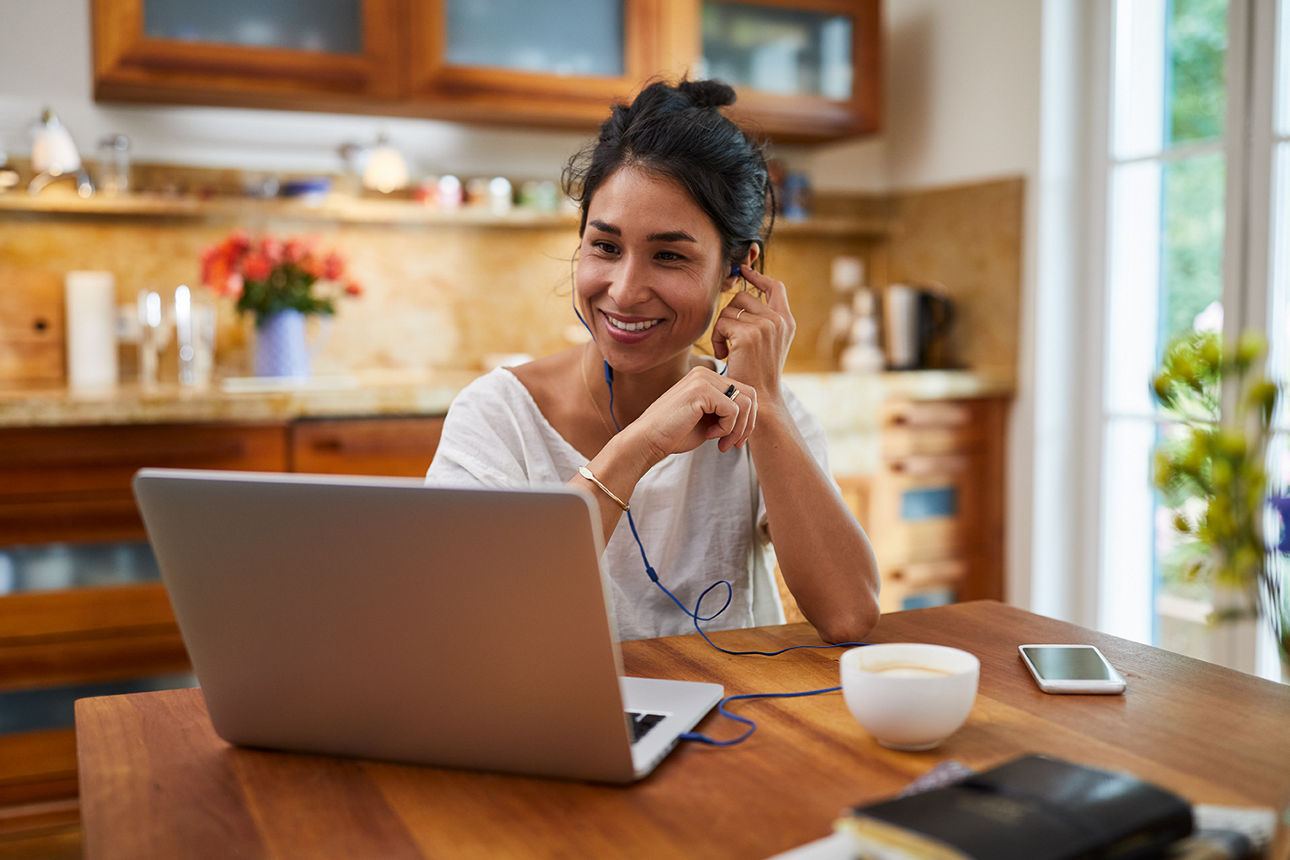 Frau sitzt im Wohnzimmer am Laptop