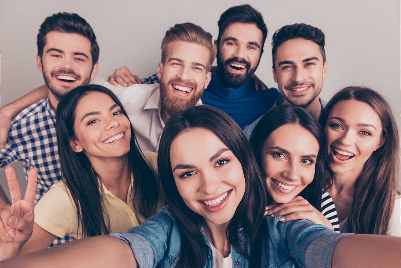 Acht lachende Menschen machen ein Selfie