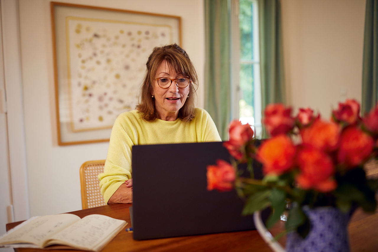 Ältere Frau sitzt am Laptop.