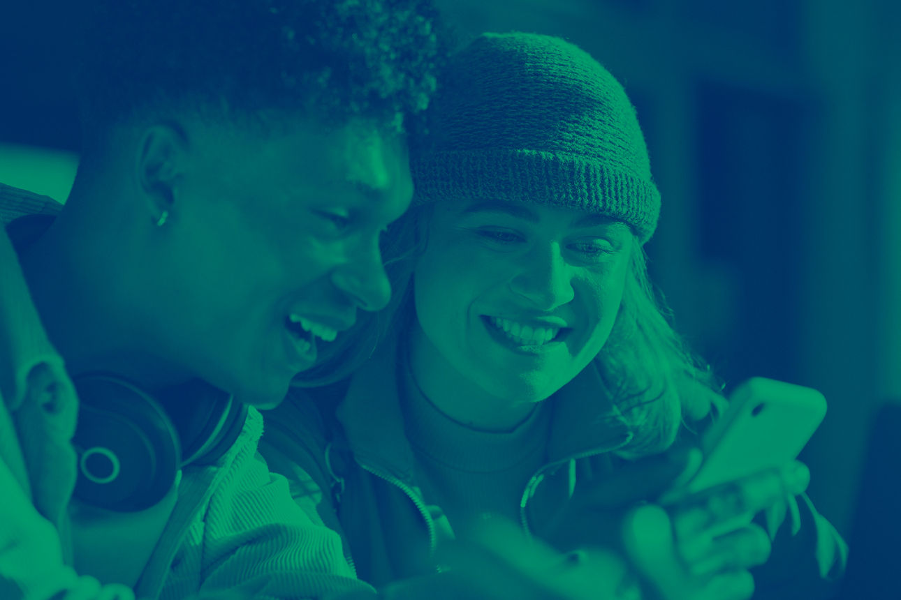 Zwei Junge Menschen lächelnd vor dem Smartphone