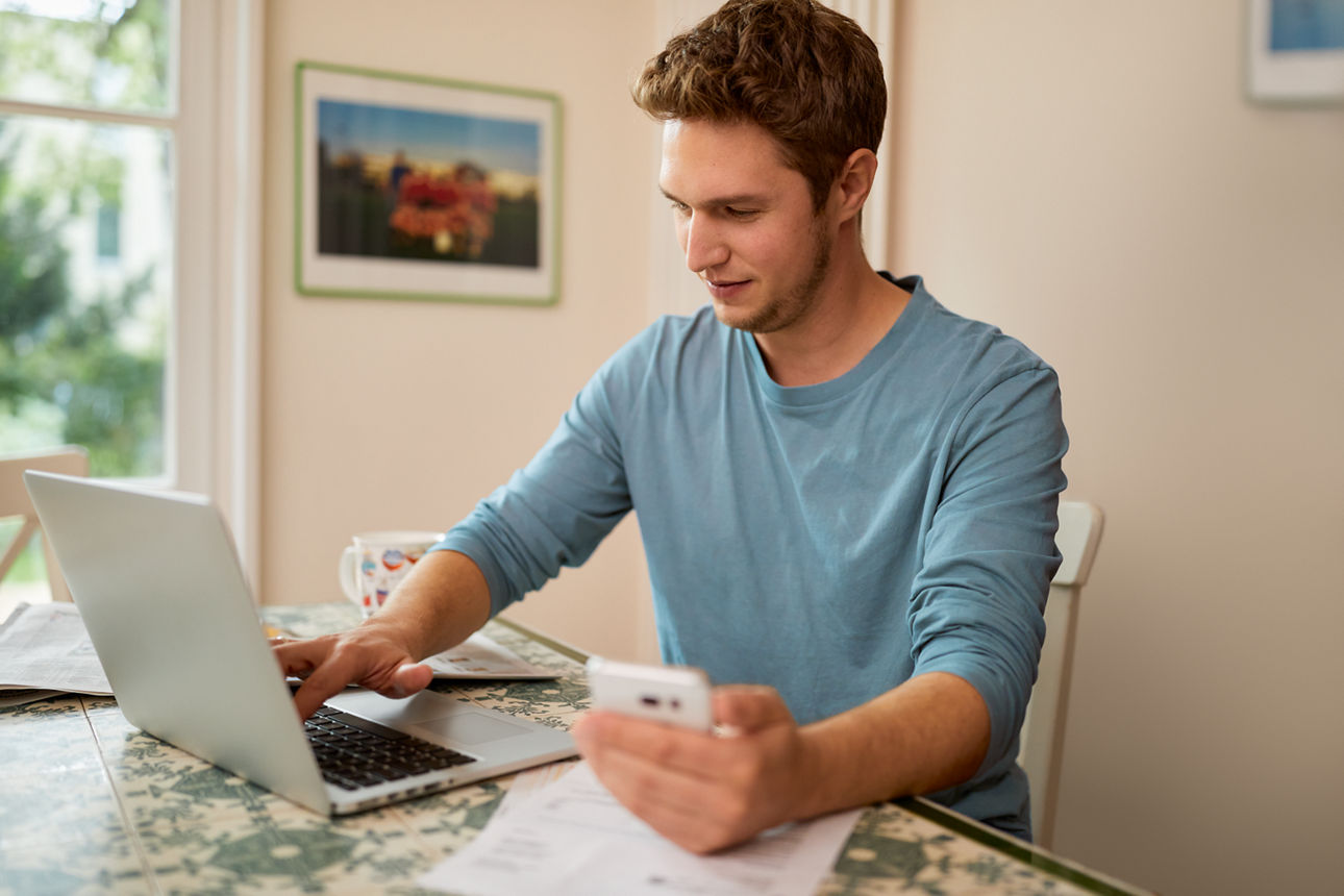 Mann mit Handy in der Hand am PC