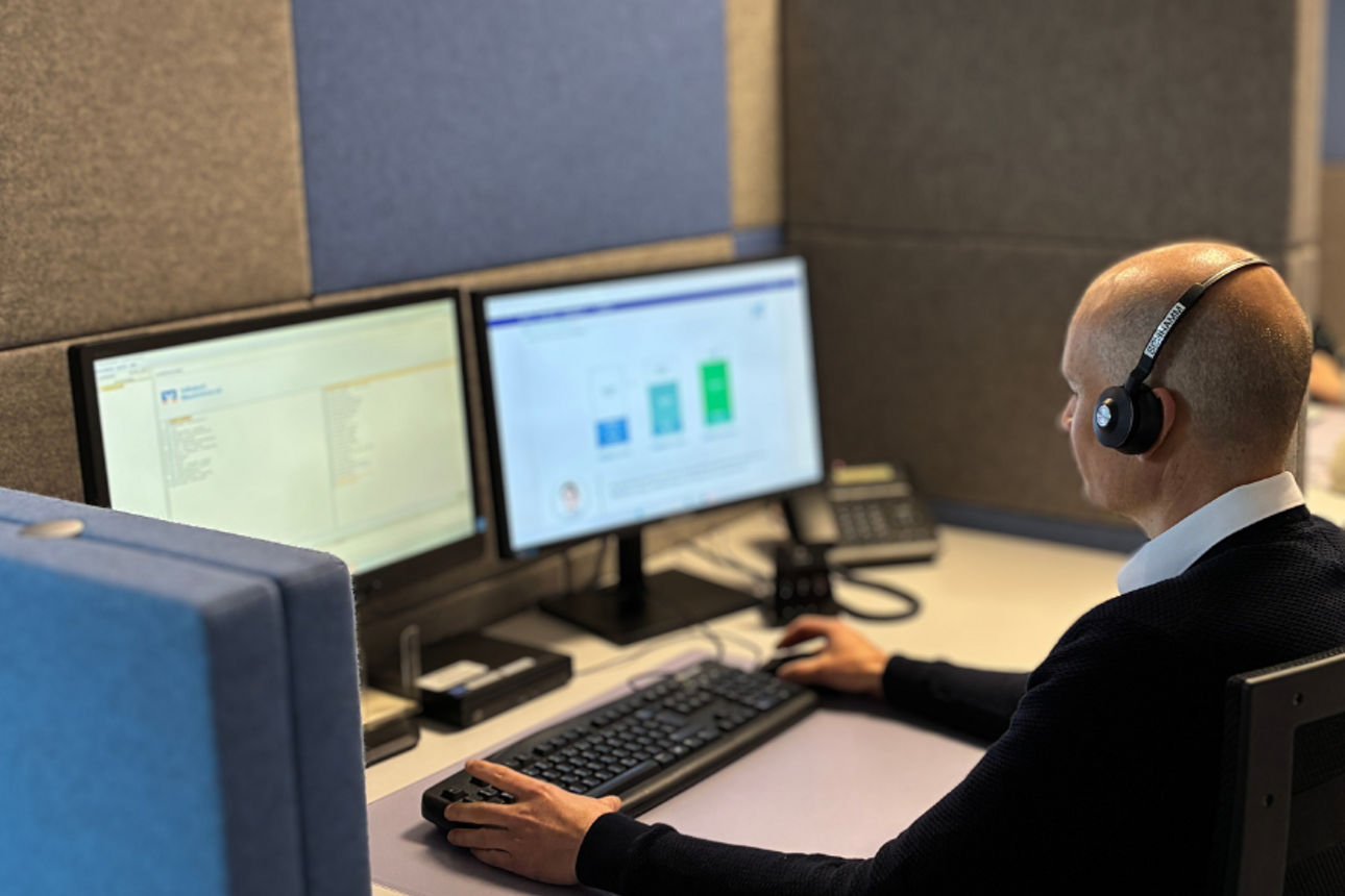 Arbeitende Mitarbeitende mit Headsets an Computern