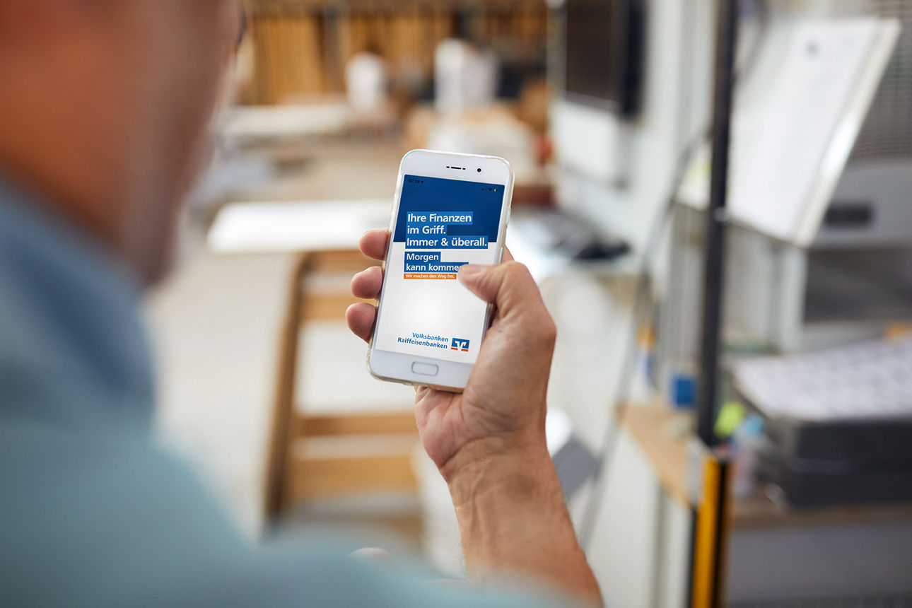 Mann schaut auf Handydisplay mit Banking App