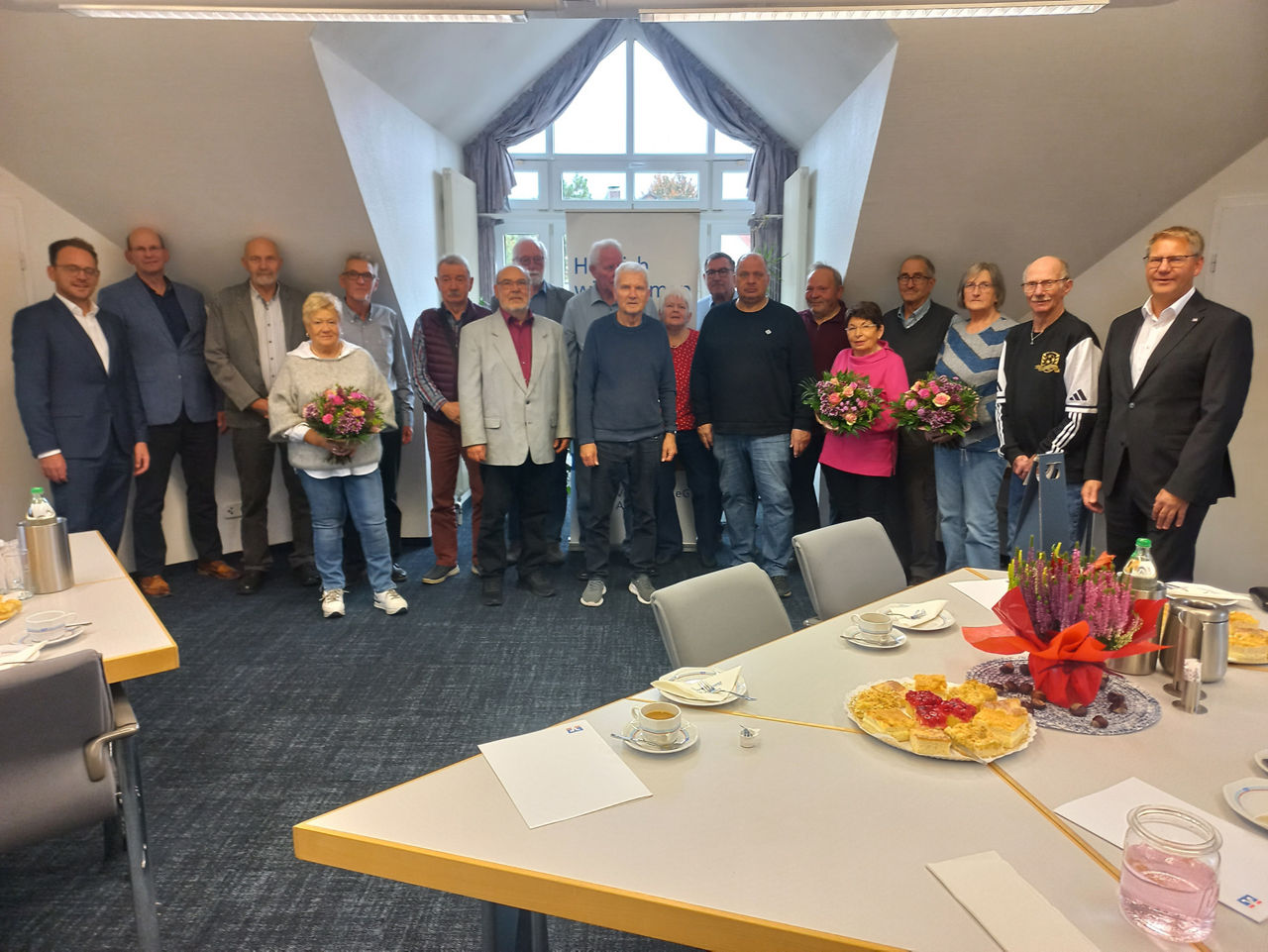 Gruppenfoto von Kollegen, die sich in einem Innenraum versammelt haben