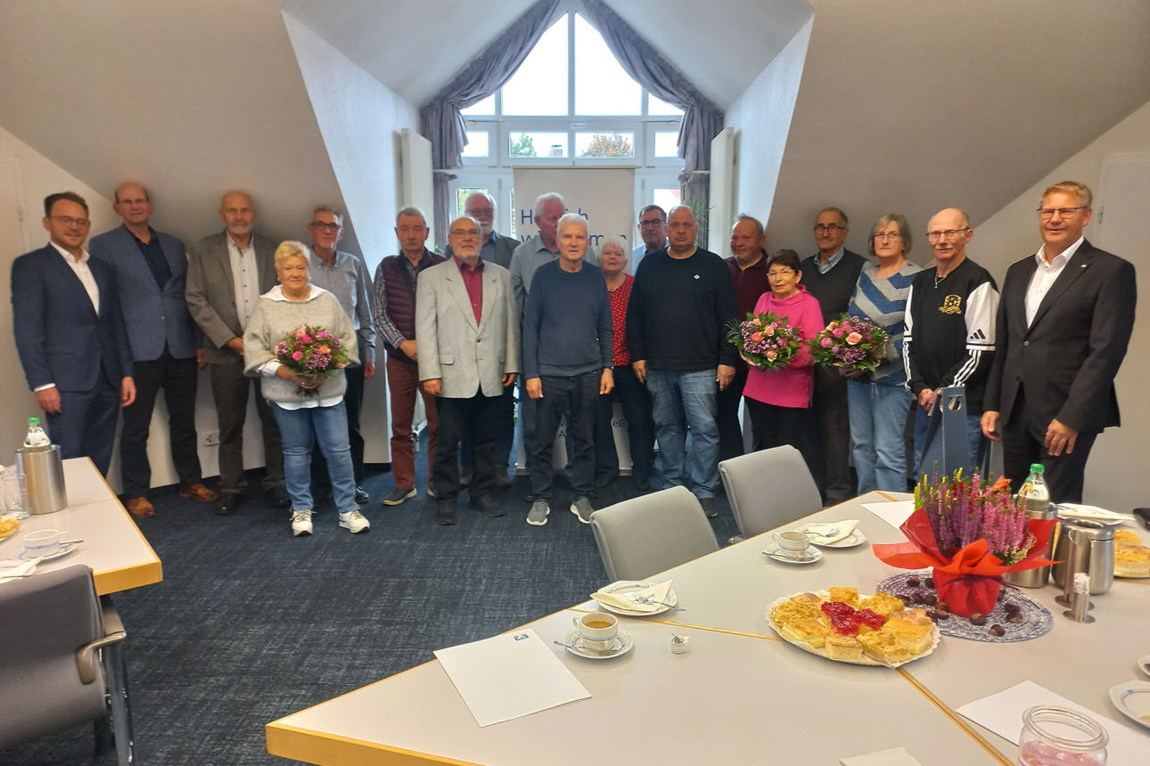Gruppenfoto von Kollegen, die sich in einem Innenraum versammelt haben