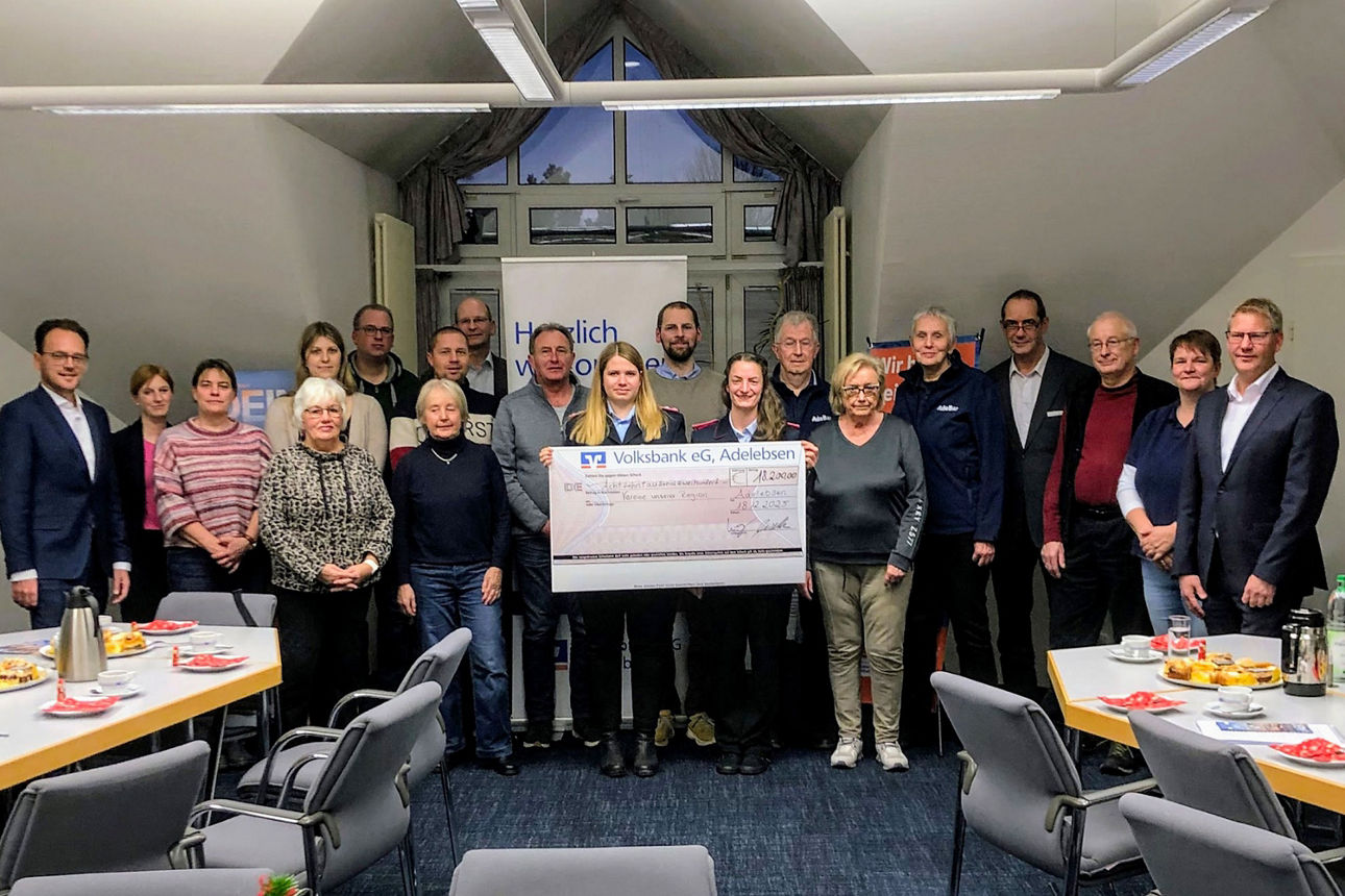 Foto von einer Gruppe von Menschen die in einem Besprechungsraum stehen. Symbolischer Scheck in Höhe von 18.200,00€ wird hochgehoben.