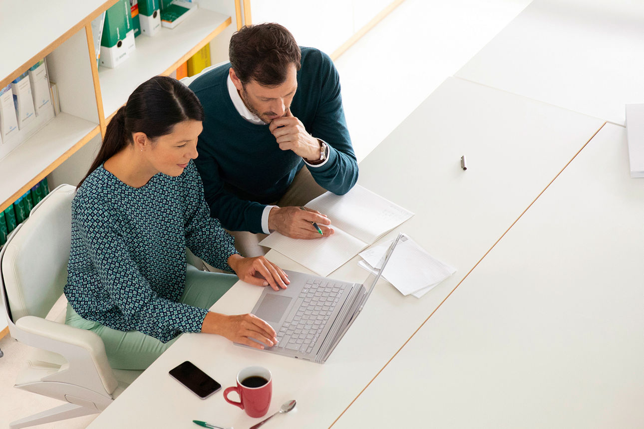 Eine Frau und ein Mann sitzen mit einem Laptop am Tisch