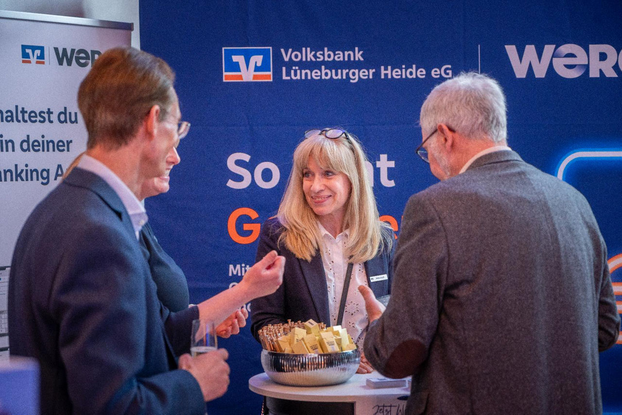 Eine Volksbankmitarbeiterin erklärt interessierten Gästen WERO am Infostand