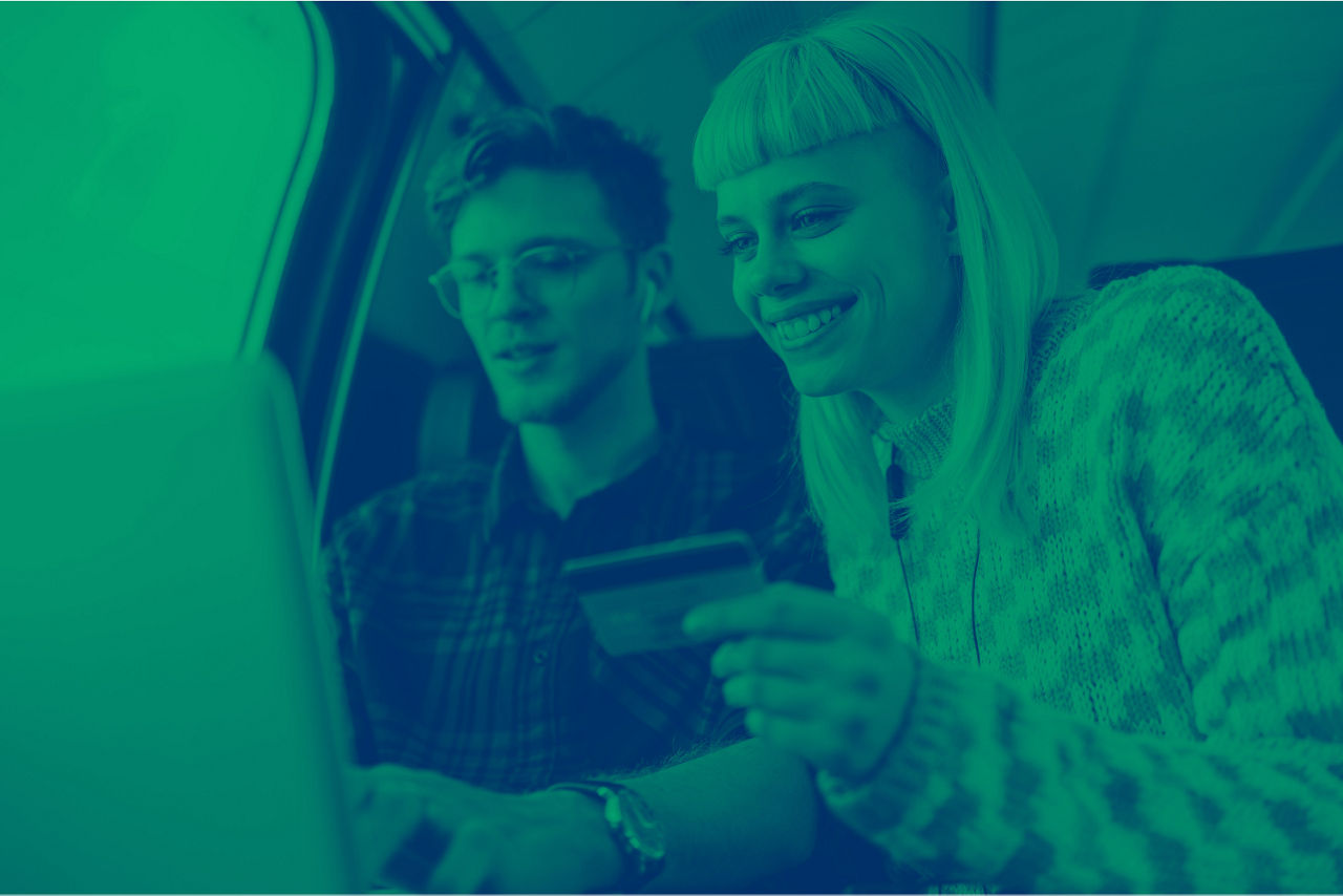 Zwei Junge Menschen lächelnd vor dem Smartphone und einem Laptop