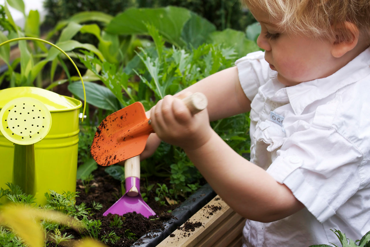 Kind mit einer Schaufel an Hochbeet