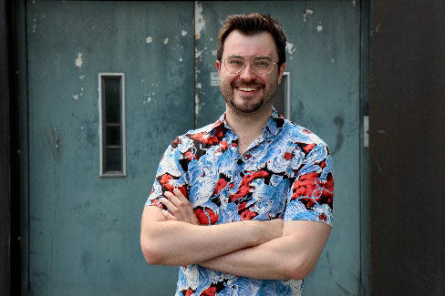 Quiz-Champion Sebastian Klussmann blickt lachend und mit verschränkten Armen in die Kamera