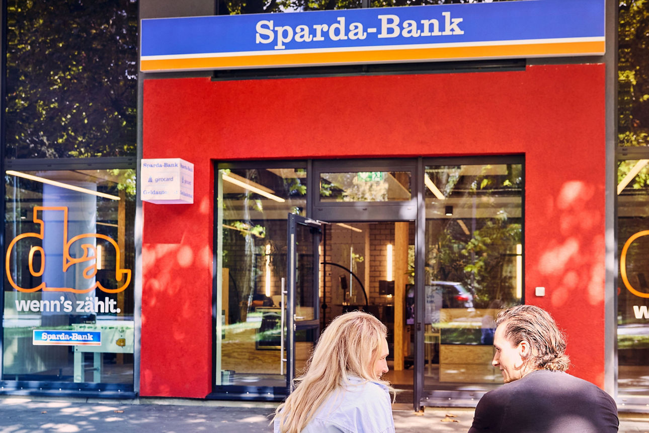 Zwei Menschen sitzen vor einer Sparda-Filiale
