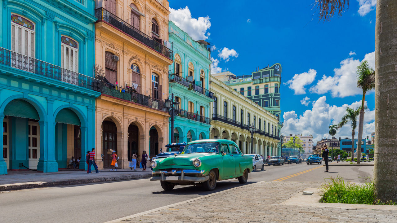 Grüner Oldtimer fährt auf der Hauptstraße in Havanna Stadt Kuba an der historischen Häuserfront vorbei - Serie Kuba Reportage