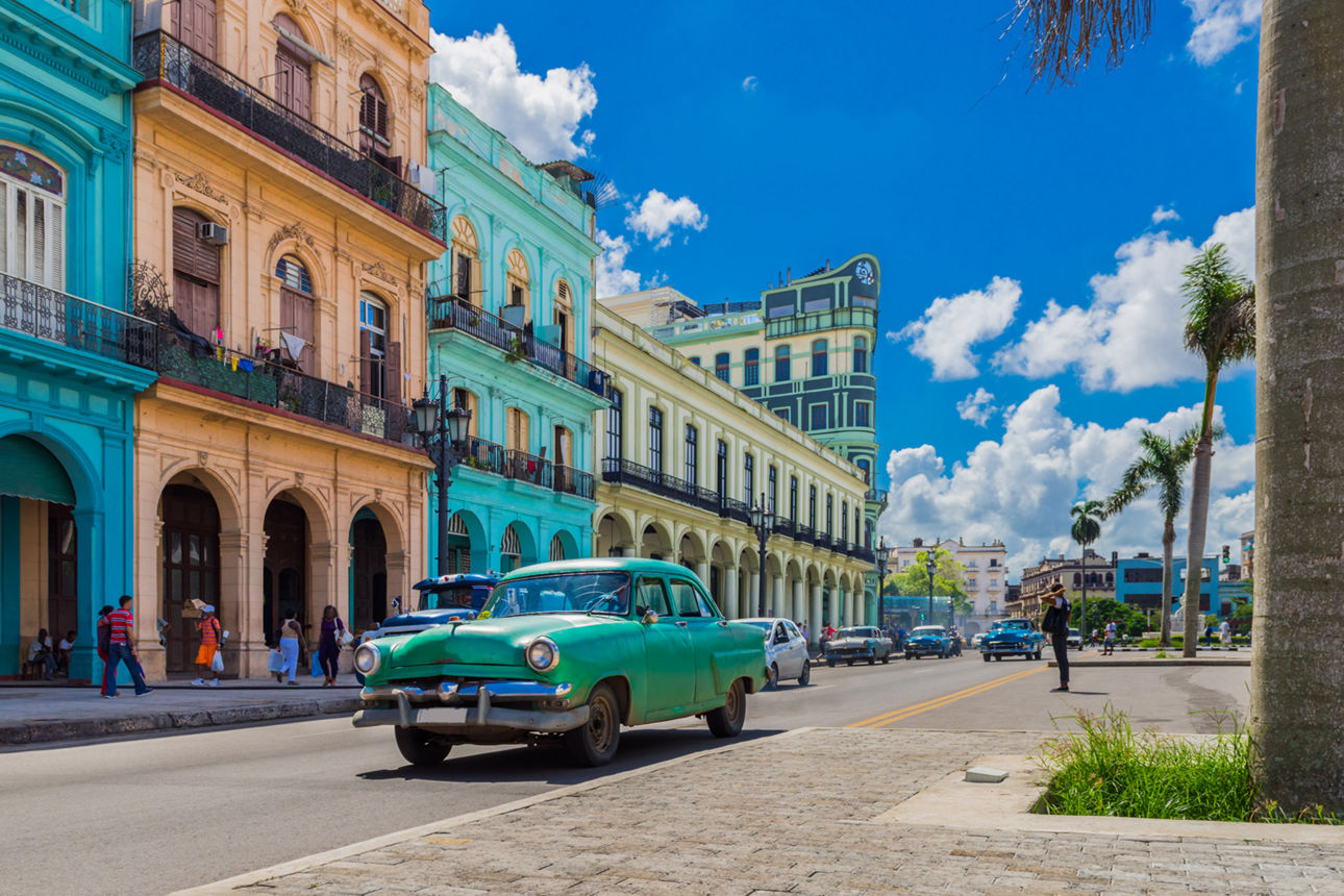 Grüner Oldtimer fährt auf der Hauptstraße in Havanna Stadt Kuba an der historischen Häuserfront vorbei - Serie Kuba Reportage