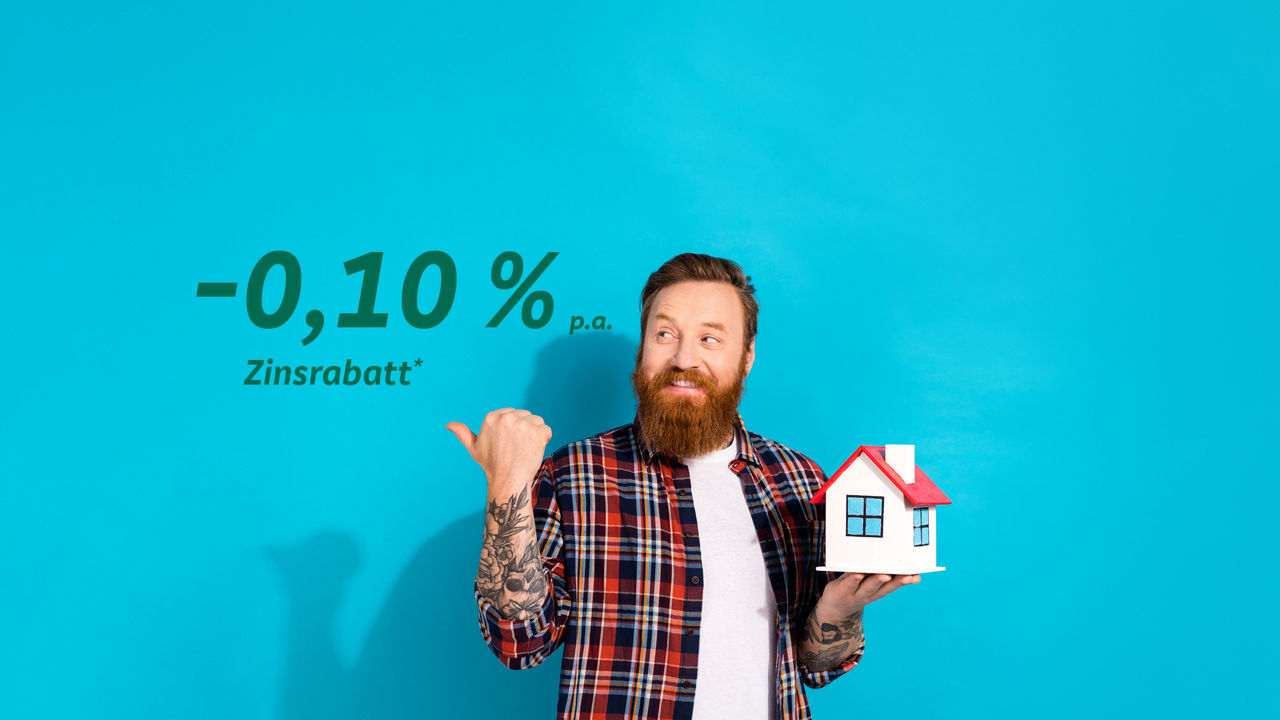 Ein Mann hält das Haus in einer Hand und mit der anderen Hand zeigt auf den Prozentsatz (Minus 0,10 % Zinsrabat)