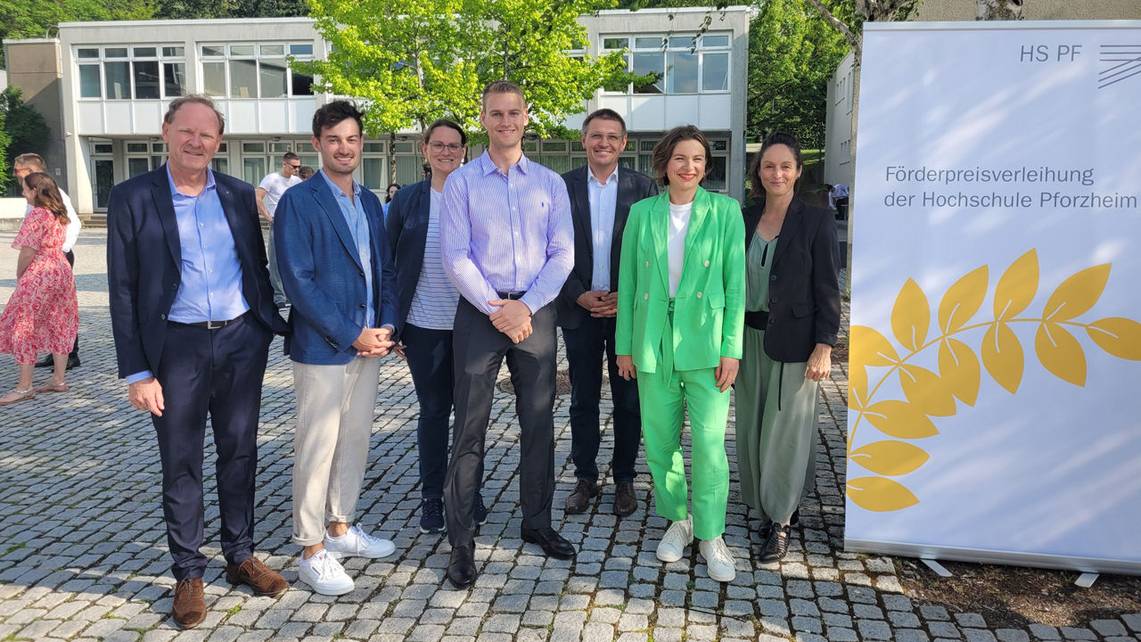  Vier Männer und drei Frauen im im Businesskleidung stehen nebeneinander- vermutlich bei einer offiziellen Veranstaltung.  