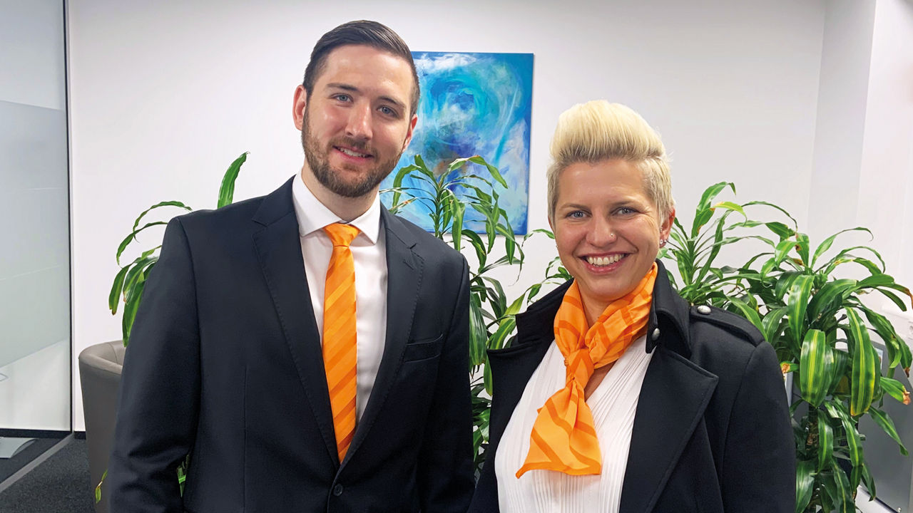Ein Mann und eine blonde Frau vor grünen Pflanzen.