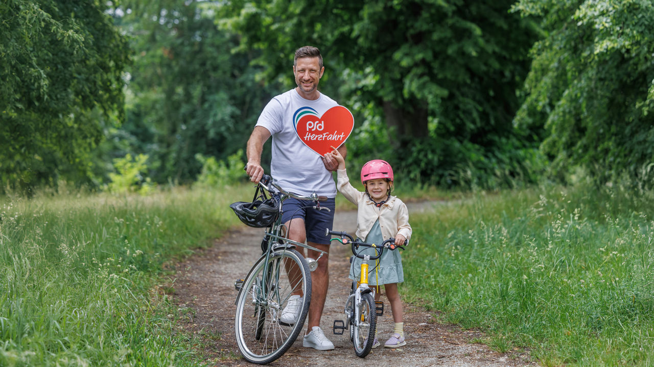 Herzfahrt / Ein Mann mit seiner Tochter mit dem Rad