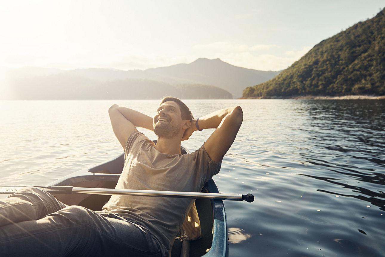 Aufnahme eines jungen Mannes, der sich in einem Boot auf einem See entspannt.