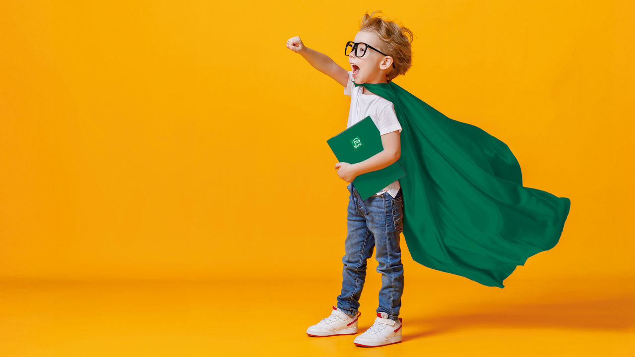 Ein Kind mit Brille in einem grünen Heldenkostüm steht mit einem grünen Buch unter dem Arm und der rechten Faust erhoben da.