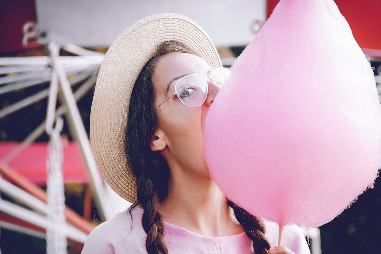 Eine junge Frau isst eine rosa Zuckerwatte.