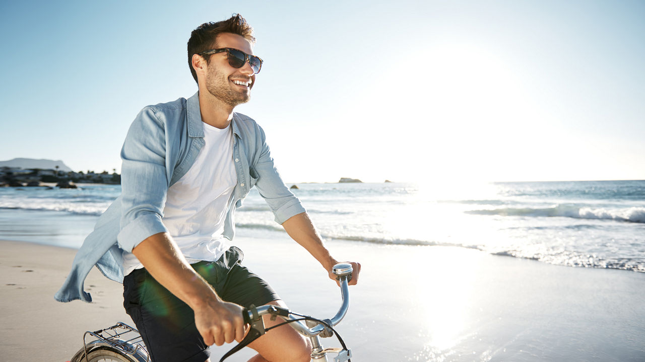 Ein Mann fährt am Strand Fahrrad.