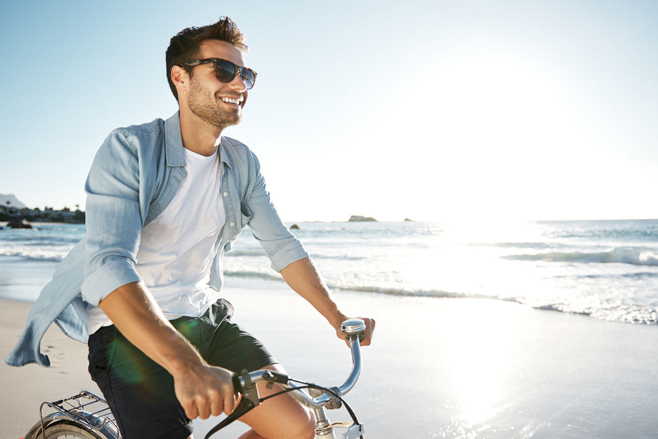 Ein Mann fährt am Strand Fahrrad.